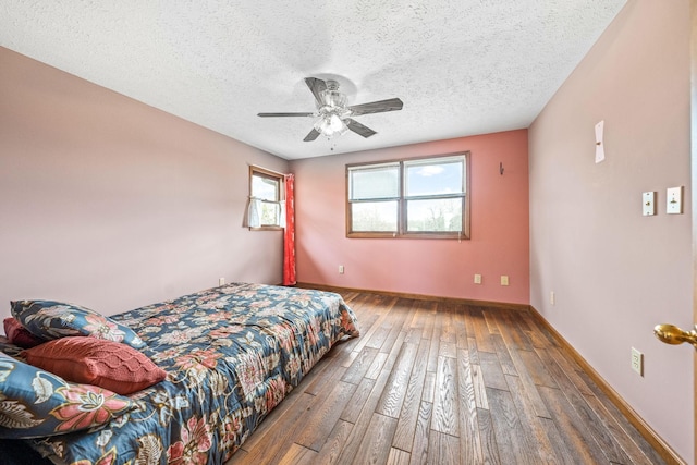 bedroom featuring ceiling fan, dark hardwood / wood-style flooring, and a textured ceiling