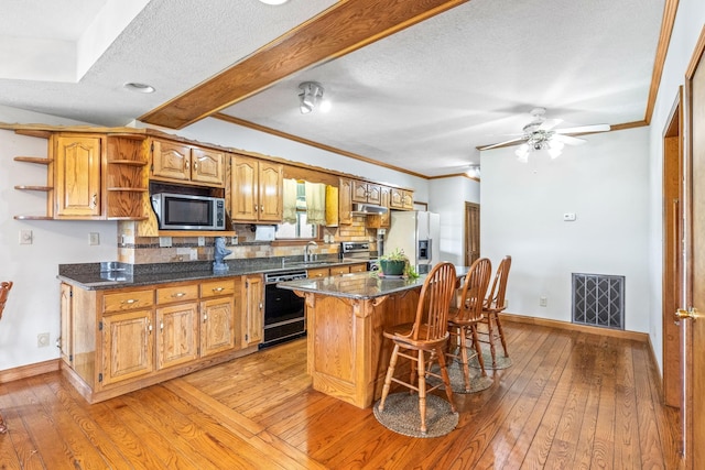 kitchen with decorative backsplash, appliances with stainless steel finishes, sink, and light hardwood / wood-style flooring