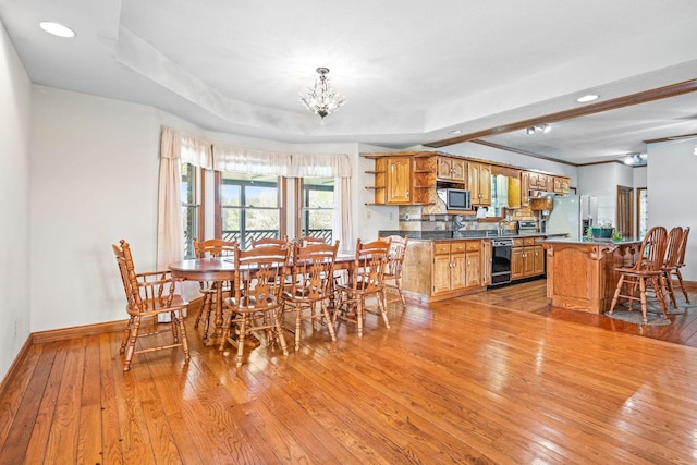 dining area with light hardwood / wood-style floors and a raised ceiling