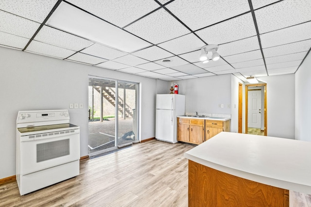 kitchen with a paneled ceiling, sink, light hardwood / wood-style floors, and white appliances