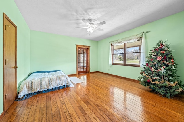 bedroom with ceiling fan, a textured ceiling, and light hardwood / wood-style flooring