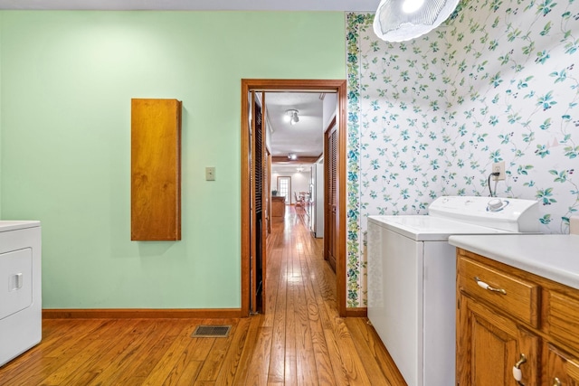 washroom with washing machine and dryer and light hardwood / wood-style floors