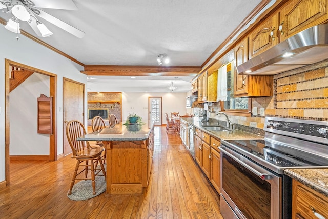 kitchen featuring a wealth of natural light, appliances with stainless steel finishes, sink, ornamental molding, and a breakfast bar