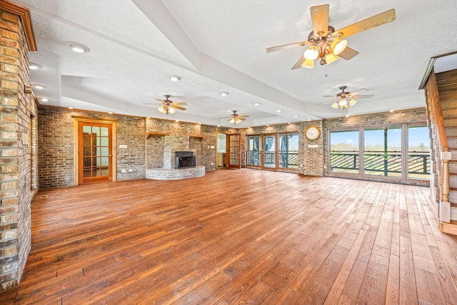 unfurnished living room with ceiling fan, wood-type flooring, a textured ceiling, and a fireplace