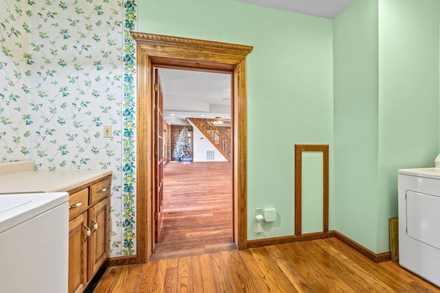 clothes washing area with cabinets, light hardwood / wood-style flooring, and washer / clothes dryer