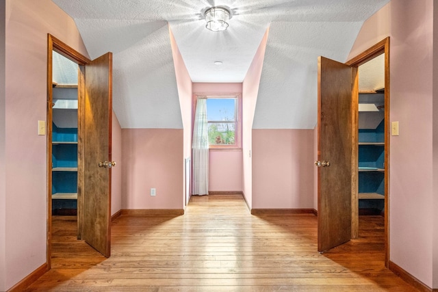 corridor with vaulted ceiling and light hardwood / wood-style flooring