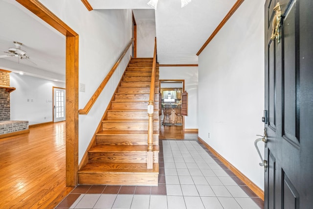 stairway with ceiling fan, tile patterned floors, and ornamental molding