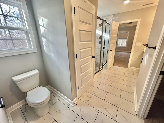 bathroom with a shower with shower door and toilet