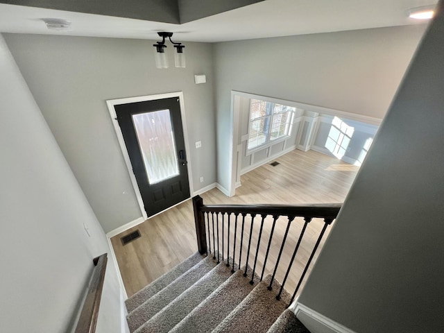 foyer entrance featuring baseboards, stairs, visible vents, and wood finished floors