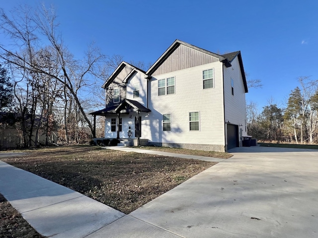 view of front of property with board and batten siding, central AC, driveway, and a garage