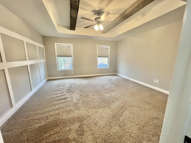 spare room featuring a ceiling fan, baseboards, a tray ceiling, and carpet flooring