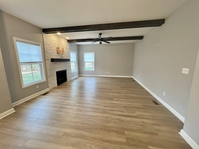 unfurnished living room with ceiling fan, a healthy amount of sunlight, and beamed ceiling