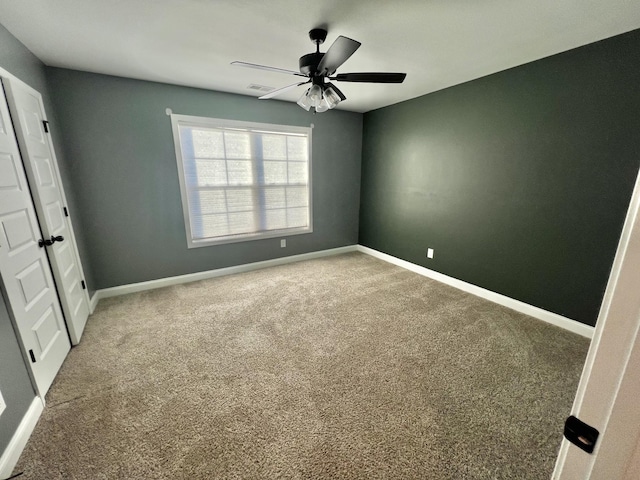 unfurnished bedroom featuring a ceiling fan, visible vents, baseboards, and carpet flooring