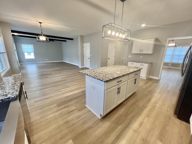 kitchen featuring decorative light fixtures, a center island, white cabinetry, light wood-type flooring, and light stone countertops