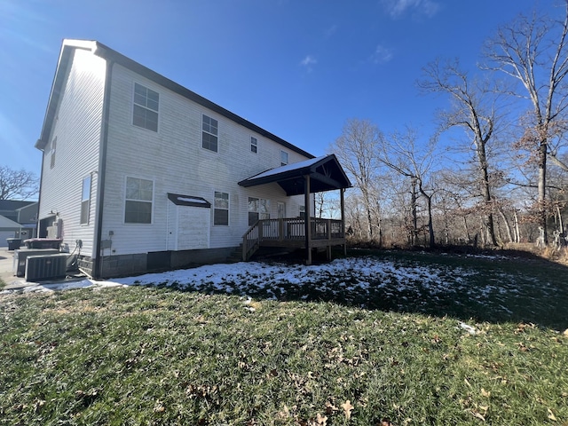 snow covered back of property with central AC unit and a yard