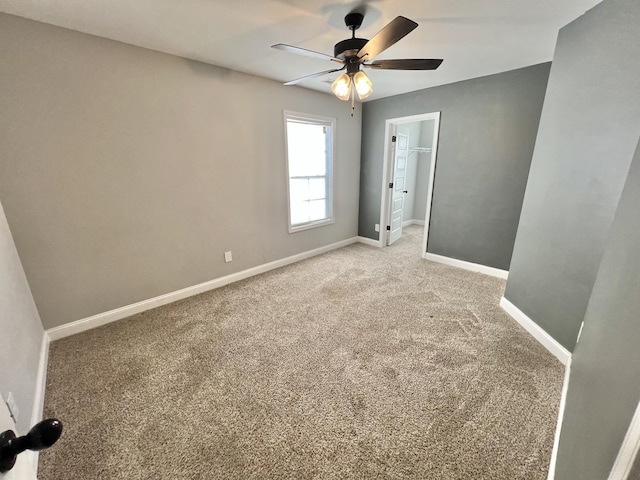 unfurnished bedroom featuring a ceiling fan, baseboards, a spacious closet, a closet, and carpet