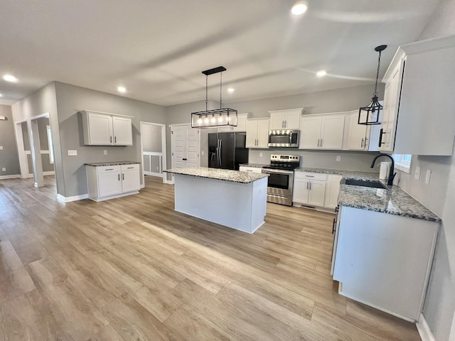 kitchen with a center island, white cabinetry, stainless steel appliances, sink, and stone countertops