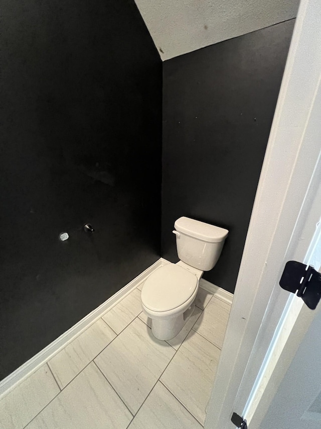 bathroom with toilet, a textured ceiling, tile patterned floors, and vaulted ceiling