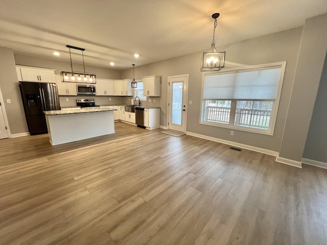 kitchen featuring appliances with stainless steel finishes, a center island, white cabinetry, and pendant lighting