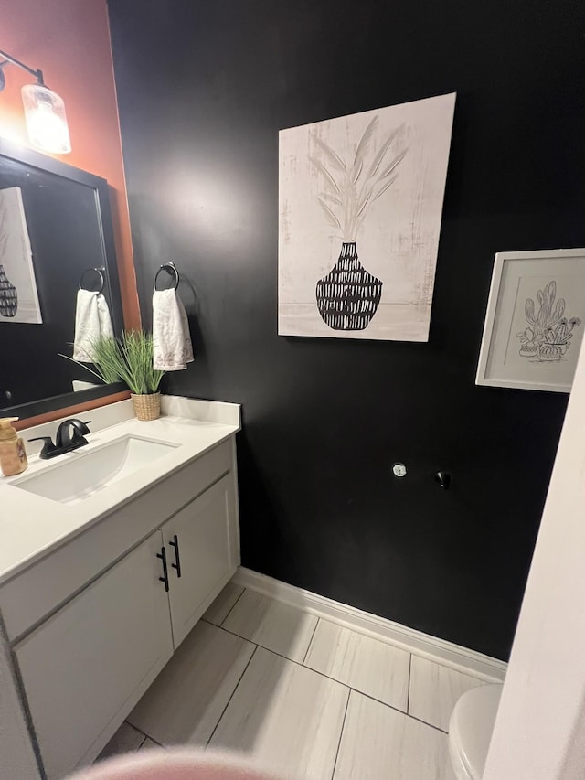 bathroom with baseboards, vanity, and toilet