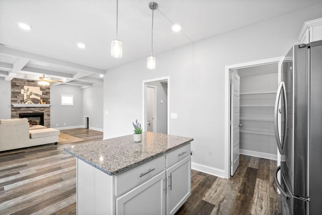 kitchen featuring a center island, beam ceiling, coffered ceiling, white cabinets, and stainless steel fridge