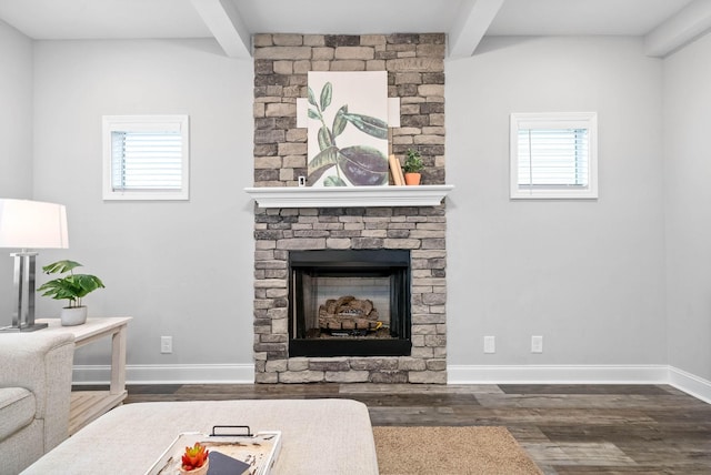 living room featuring dark wood-type flooring, a stone fireplace, and beamed ceiling