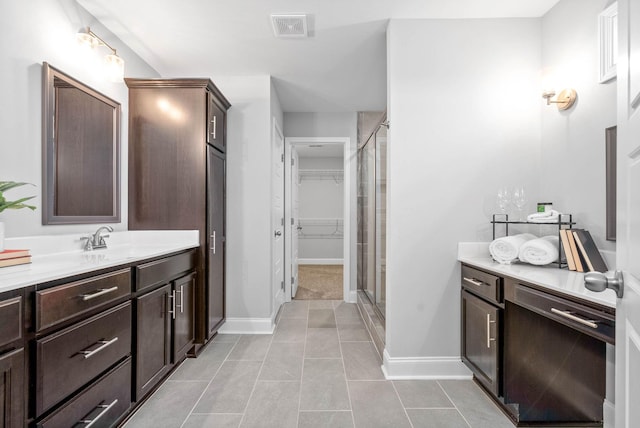 bathroom with a shower with shower door, vanity, and tile patterned flooring