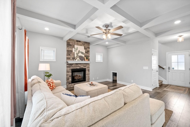 living room with dark hardwood / wood-style floors, plenty of natural light, a stone fireplace, and coffered ceiling