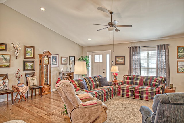 living room with ceiling fan, plenty of natural light, light wood-type flooring, and vaulted ceiling