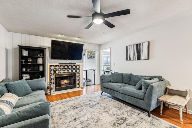 living room featuring wood-type flooring, a tile fireplace, and a textured ceiling