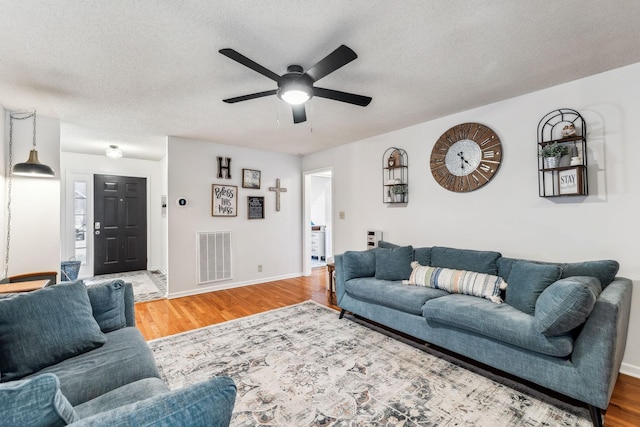 living room featuring ceiling fan, hardwood / wood-style floors, and a textured ceiling