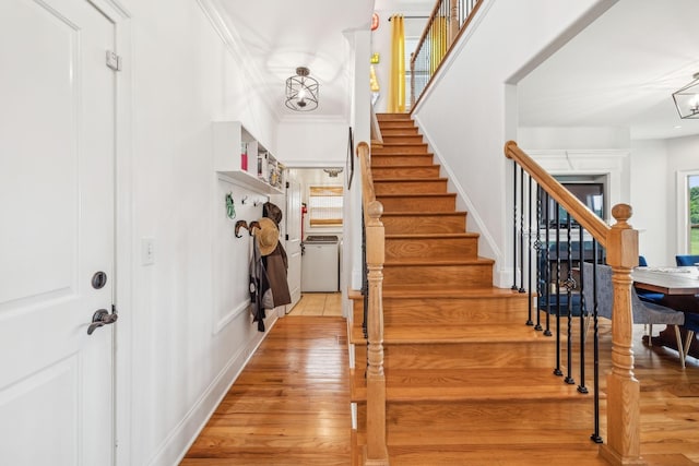 stairway with crown molding, a chandelier, and hardwood / wood-style floors