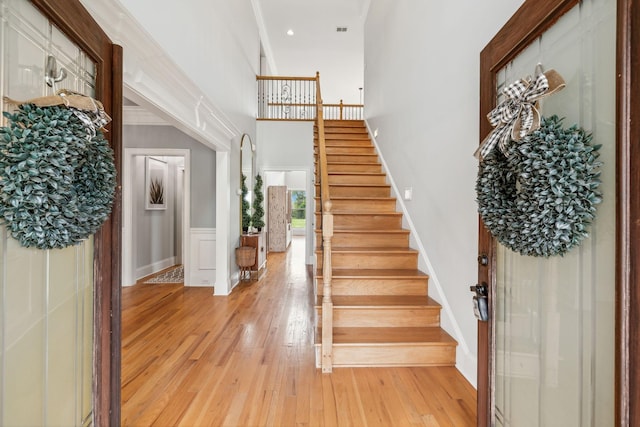 foyer entrance featuring a high ceiling, light hardwood / wood-style flooring, and ornamental molding