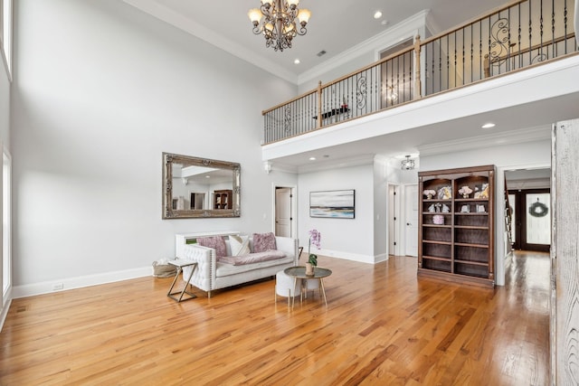 living room with crown molding, a notable chandelier, a high ceiling, and hardwood / wood-style flooring