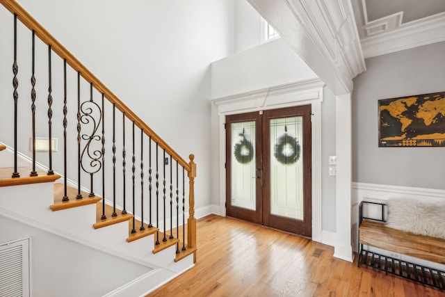 foyer with french doors, crown molding, and light hardwood / wood-style flooring