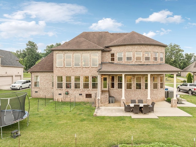 back of property featuring a trampoline, a patio area, and a yard