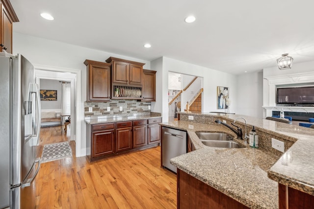 kitchen with stainless steel appliances, tasteful backsplash, light hardwood / wood-style floors, sink, and light stone counters