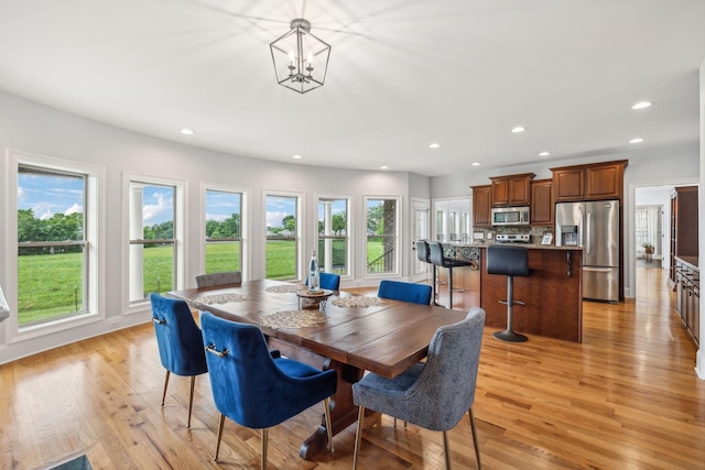 dining area with light hardwood / wood-style floors and an inviting chandelier