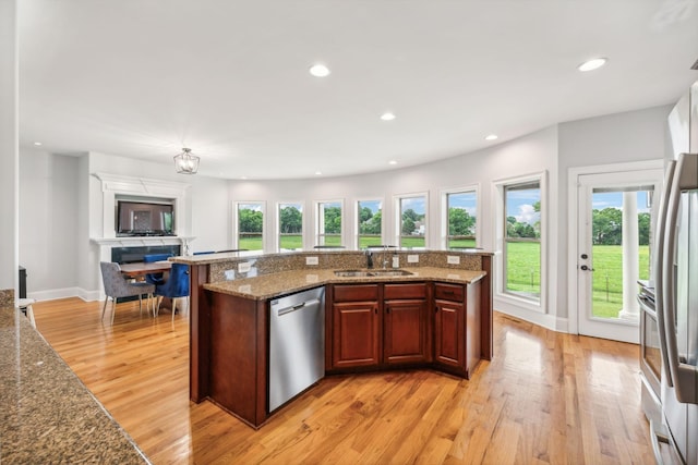 kitchen featuring sink, stone countertops, light wood-type flooring, fridge, and stainless steel dishwasher