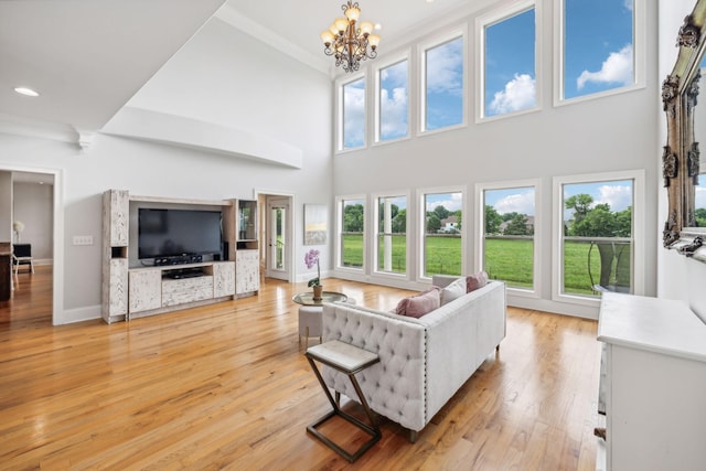 living room featuring light hardwood / wood-style floors, a high ceiling, a wealth of natural light, and an inviting chandelier