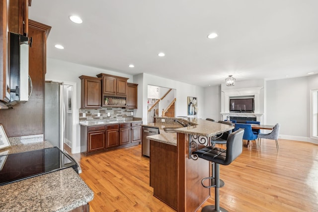 kitchen featuring a center island, a breakfast bar, sink, light hardwood / wood-style flooring, and stainless steel appliances