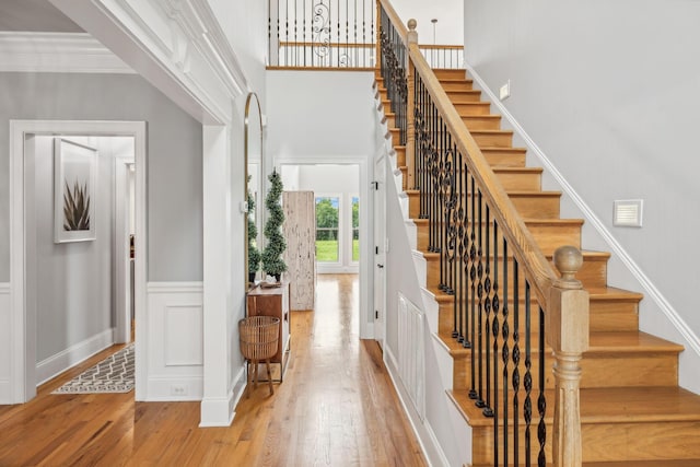 stairway with ornamental molding and wood-type flooring