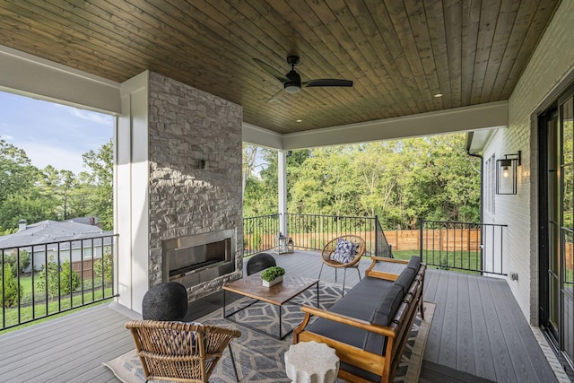 deck with ceiling fan and an outdoor stone fireplace