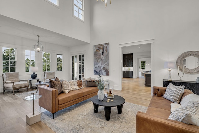 living room featuring a high ceiling, light hardwood / wood-style flooring, and a notable chandelier