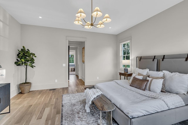 bedroom with an inviting chandelier and light hardwood / wood-style flooring