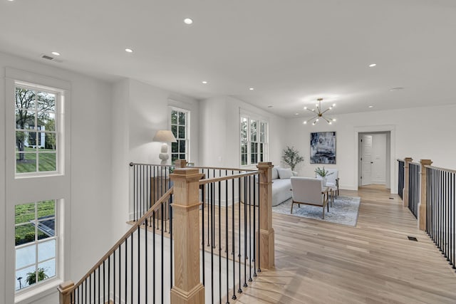 hallway featuring an inviting chandelier and light hardwood / wood-style floors