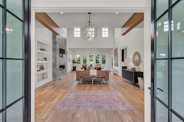 dining area with a large fireplace, built in features, wood-type flooring, and a notable chandelier