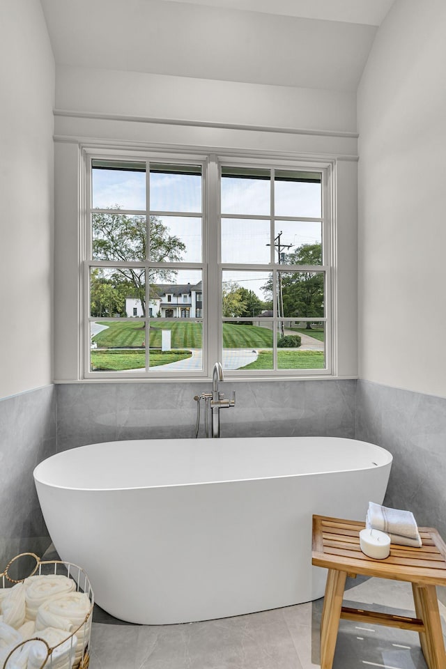 bathroom featuring tile walls, a bathtub, and a healthy amount of sunlight