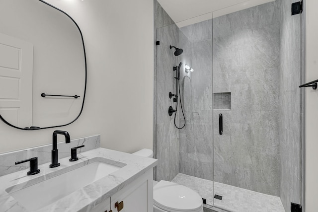 bathroom featuring toilet, a shower with shower door, and vanity