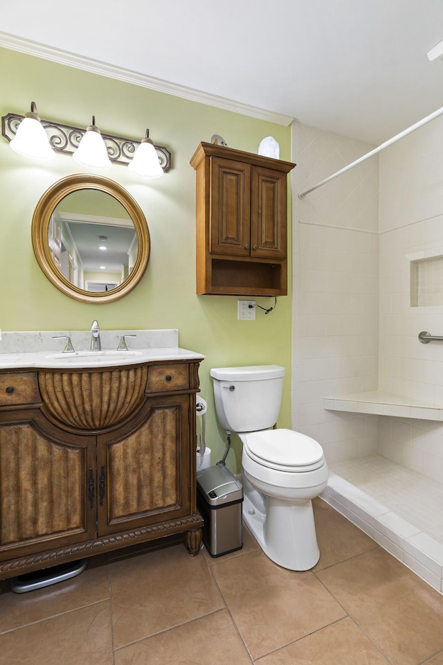 bathroom with toilet, tile patterned flooring, a tile shower, and vanity